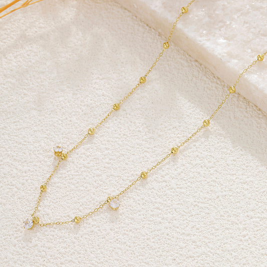 Collier doré chaîne fine orné de boules lisses avec 3 strass à l'avant