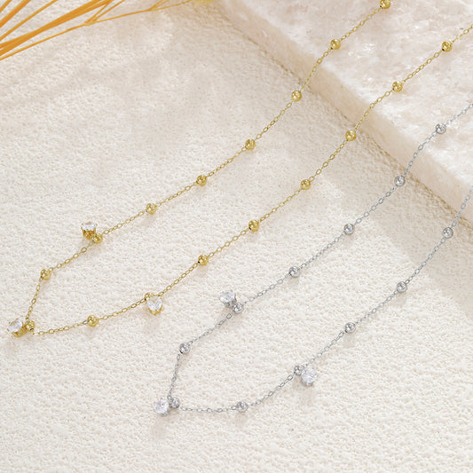 Collier doré chaîne fine orné de boules lisses avec 3 strass à l'avant