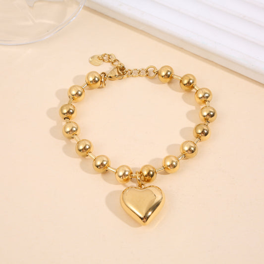 Bracelet doré à grosses perles rondes avec pendentif cœur bombé