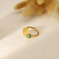 Bague dorée matte avec ouverture à l'avant et pierre verte