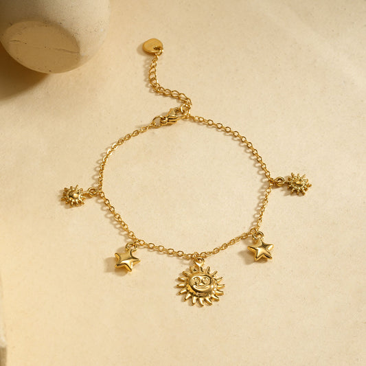 Bracelet chaîne fine dorée pendentifs soleil central encadré par étoiles et soleils