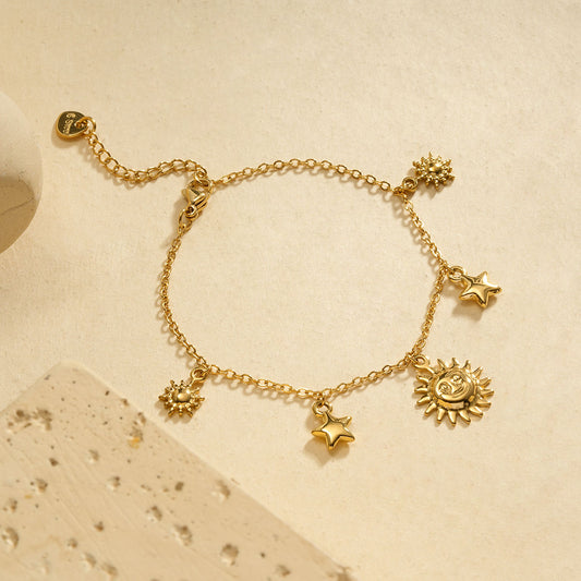 Bracelet chaîne fine dorée pendentifs soleil central encadré par étoiles et soleils