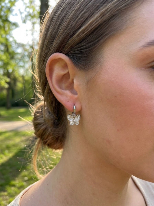 Boucles d'oreilles mini créoles argentées avec pendentifs papillon serti d'un strass