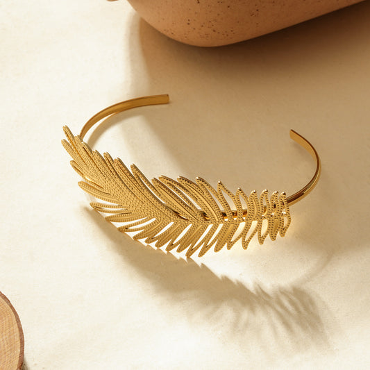 Manchette dorée ouverte motif feuille tropicale