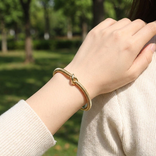 Bracelet jonc doré texturé effet ressort orné d’un nœud central