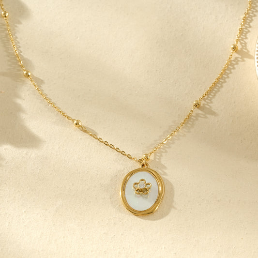 Collier fin doré orné de perles boules et médaille florale