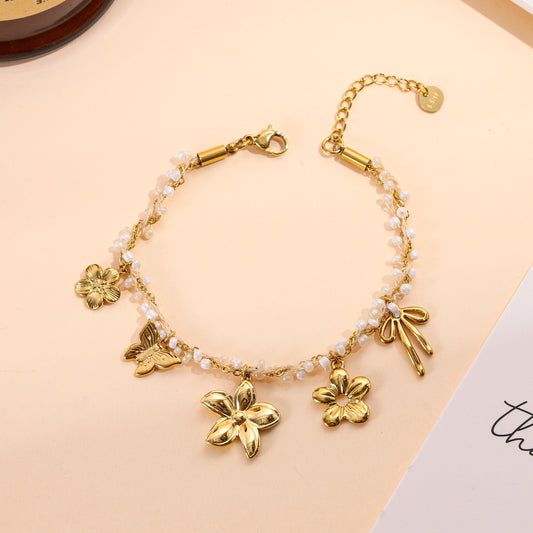 Bracelet chaîne doré orné de perles et pendentifs floraux