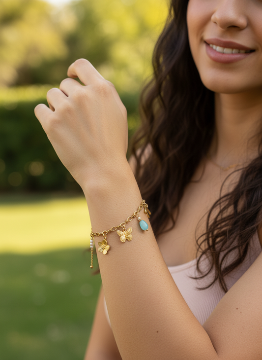 Bracelet doré à charms papillon, fleur et pierre bleue