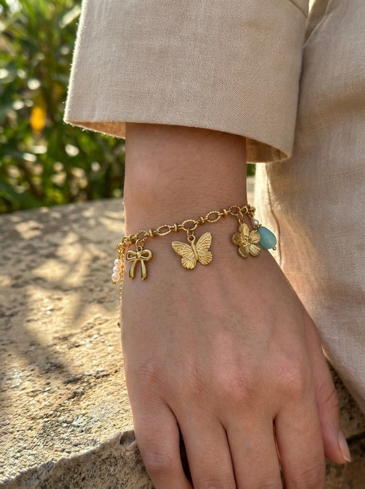 Bracelet doré à charms papillon, fleur et pierre bleue