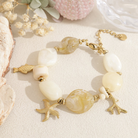 Bracelet doré perles en résine beige pendentifs marins