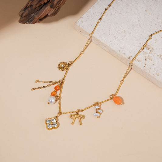 Collier doré à charms perles oranges, nœud et fleur strassée