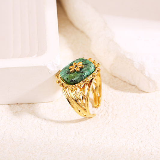 Bague dorée ajourée avec pierre rectangulaire arrondie verte et motif fleur centrale