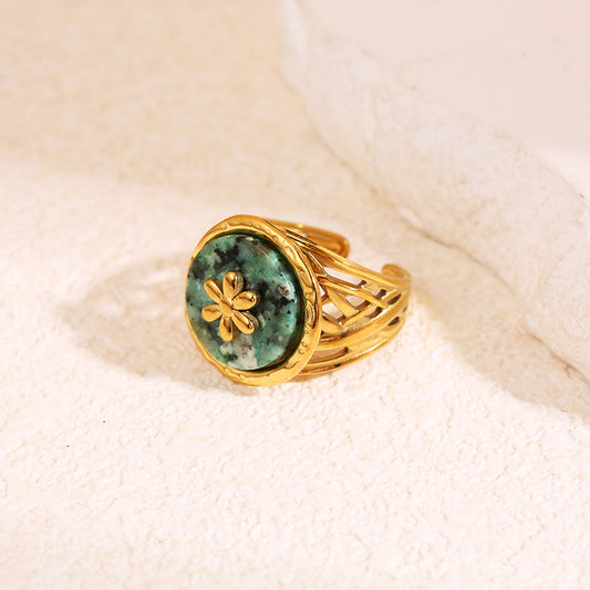 Bague dorée ajourée avec pierre ronde verte et motif fleur centrale