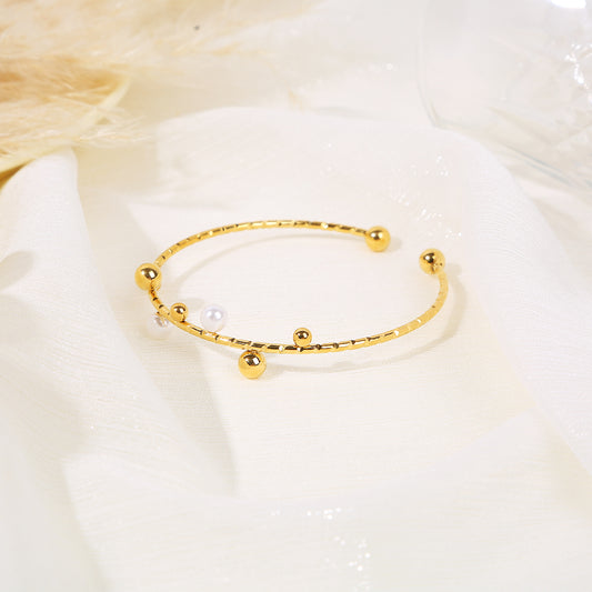 Bracelet jonc ouvert doré orné de billes dorées et perlées avec billes dorées aux extrémités