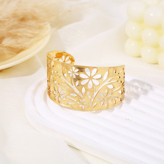 Bracelet manchette doré ajustable orné de fleurs et de branches avec feuilles ajourées
