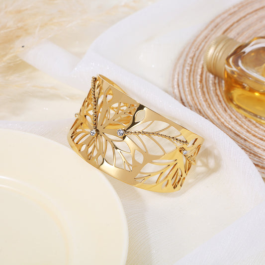 Bracelet manchette doré ajustable orné de feuilles ajourées et de lignes de strass