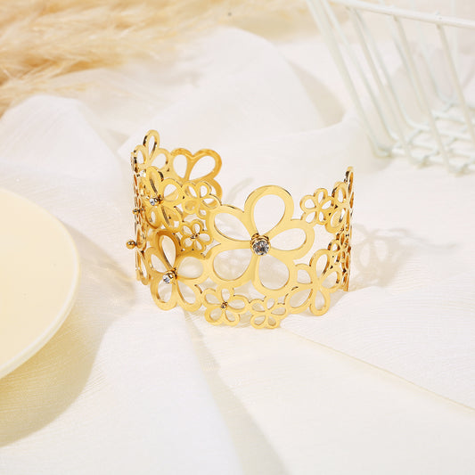 Bracelet manchette doré ajustable orné de différentes tailles de fleurs ajourées avec strass
