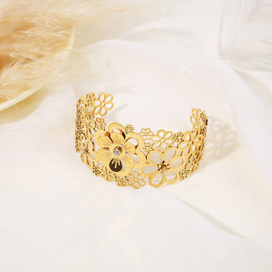 Bracelet manchette doré ajustable orné de différentes tailles de fleurs détaillées ajourées