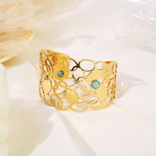 Bracelet manchette doré ajouré motif anneaux entrelacés, orné de pierres turquoise et de strass blancs