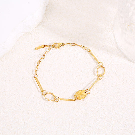 Bracelet chaîne dorée à maillons longs et ovales texturés avec médaillon feuille gravée