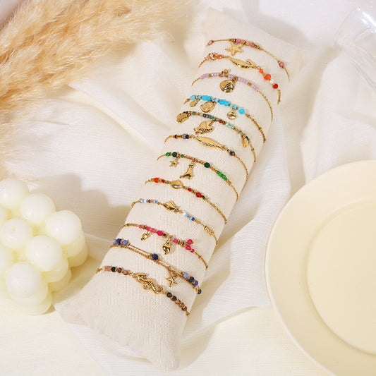 Lot de 12 bracelets dorés colorés thème plage avec pierres sur oreiller