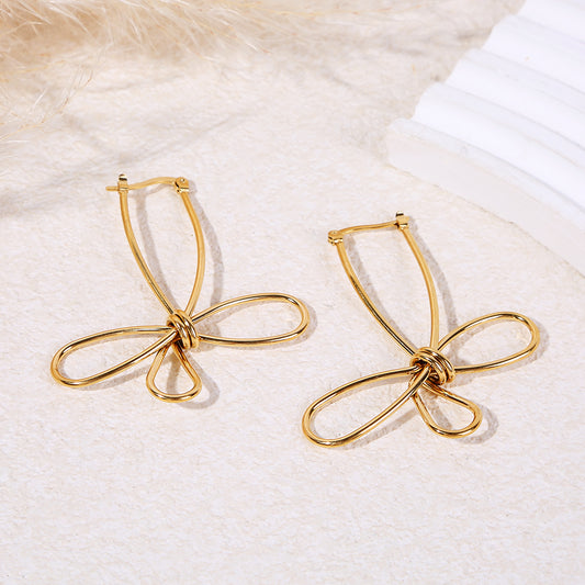 Boucles d'oreilles pendantes dorées fil métal formant un nœud papillon minimaliste
