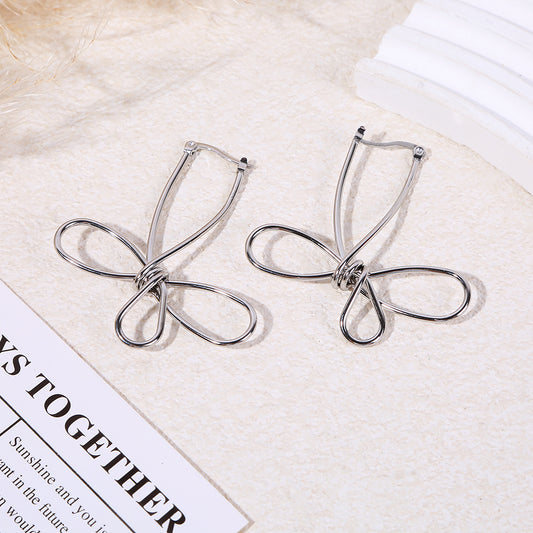 Boucles d'oreilles pendantes argentées fil métal formant un nœud papillon minimaliste