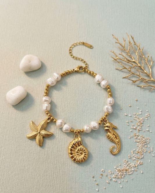 Bracelet doré avec perles structurées et charms marins