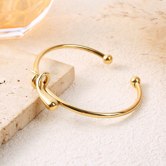 Bracelet jonc ajustable doré avec nœud central sculpté et extrémités boule