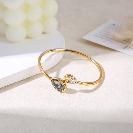 Bracelet manchette amovible dorée ouvert par l'avant avec cristaux de verres en goutte blanc et gris