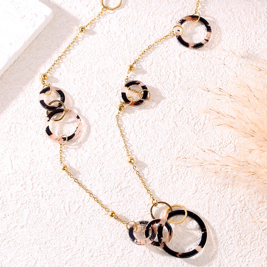 Collier sautoir chaîne dorée orné d'anneaux ronds aux motifs animaliers et dorés